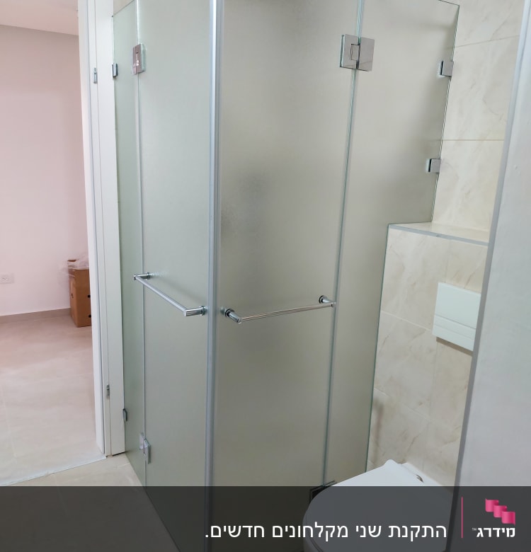 מקלחון זכוכית עם דלתות מתכת בחדר אמבטיה